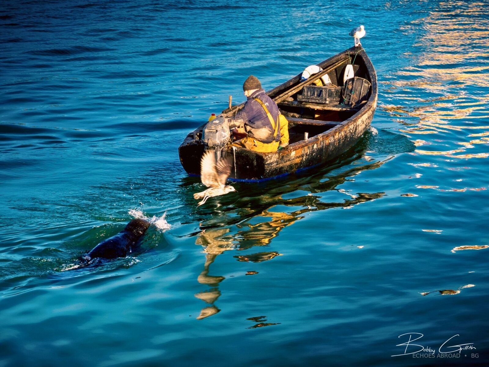 A fisherman working beside a blue boat in Howth Harbour, Ireland